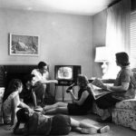 Blakc and white picture of 1958 family gathered around the television.